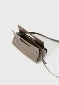 Καφέ δερμάτινη τσάντα χειρός με δομημένο σχέδιο, κλείσιμο με κορυφαίο φερμουάρ και δύο χερούλια. Διαθέτει αποσπώμενο λουρί και κομψή, λεία υφή.