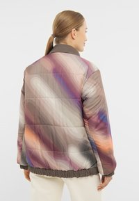 Padded bunda s hnedým, fialovým a oranžovým abstraktným vzorom. Má kontrastný tmavý golier a elastický spodný okraj.