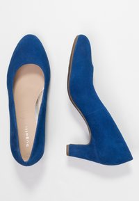 Escarpins en daim bleu avec un bout rond et un talon moyen en bloc. Doublure intérieure lisse et marque subtile sur la semelle intérieure.