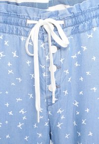 Hellblaue Shorts mit einem weißen Vogelmuster, elastischem Bund mit Kordelzug und fünf weißen Knöpfen vorne.