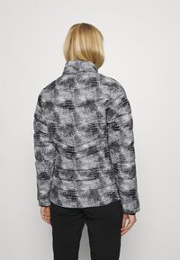 Kurtka puchowa w czarno-białą kratę houndstooth z wysokim kołnierzem, teksturowaną powierzchnią i dopasowanym krojem.