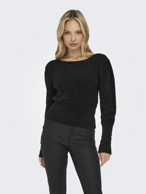 Pull en peluche noir avec un col bateau et des manches longues, fabriqué en matériau doux, associé à un pantalon noir ajusté.