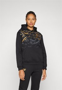 Sweatshirt preto com uma sobreposição texturizada em padrões dourados e cinzentos, bolso canguru e capuz com cordão; combinado com calças de moletom pretas a condizer.