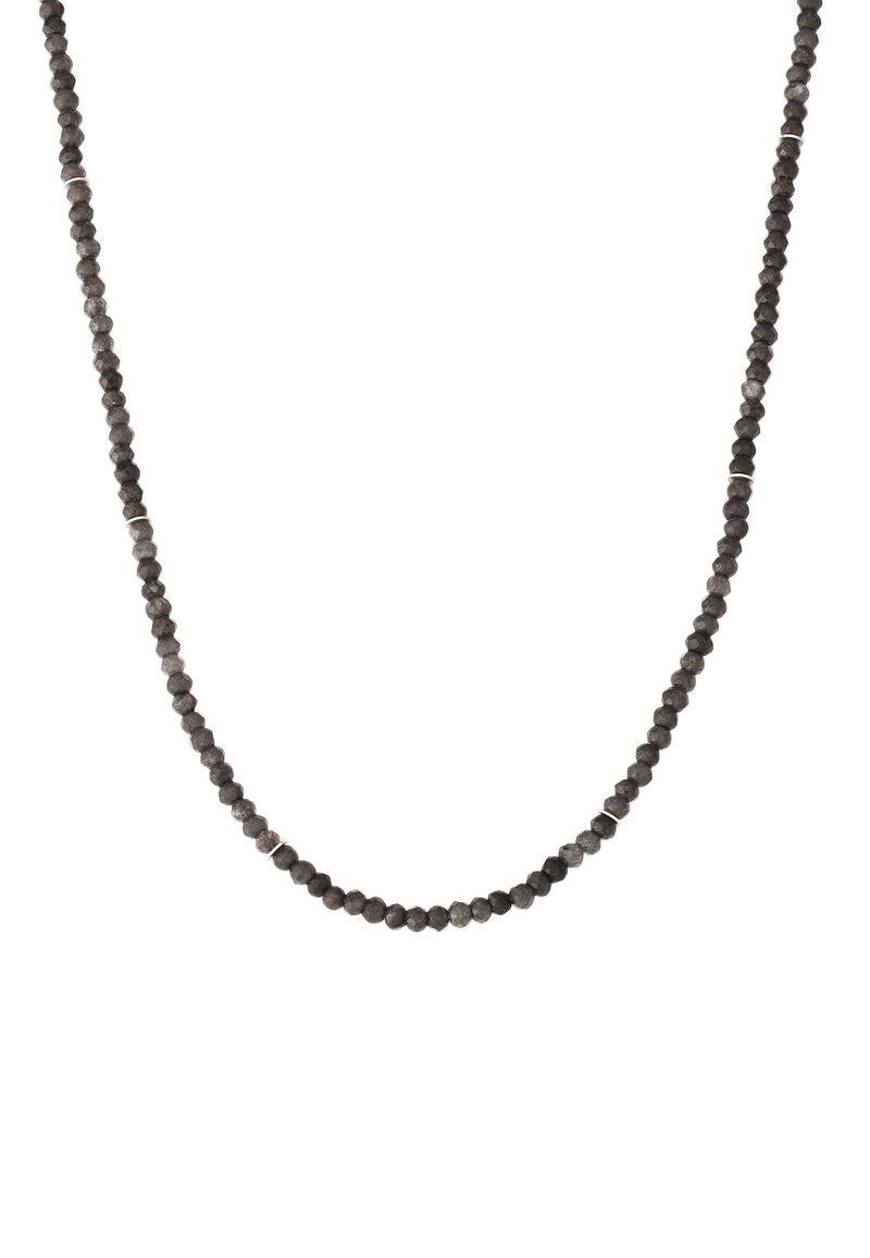 Juodų facetuotų brangakmenių vėrinys, sudarytas iš apvalių karoliukų su kartais pasitaikančiais sidabro akcentais, suformuotas paprastu, nepertraukiamu dizainu.