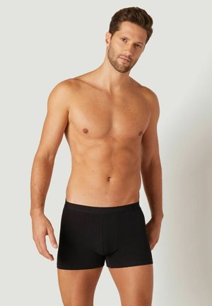 Boxers noirs en tissu doux, avec un ajustement confortable et une taille élastique. Texture lisse, design minimaliste, sans motifs ni accents.