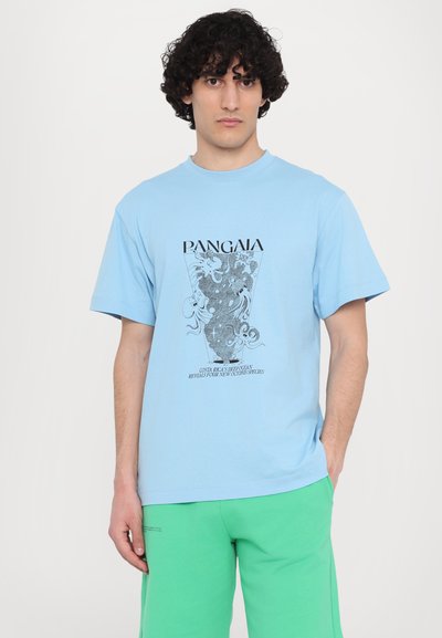 T-shirt en coton bleu clair à manches courtes, avec un design graphique noir et du texte sur le devant, associé à un short vert.