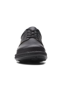 Schwarze Leder Schnürschuhe mit abgerundeter Spitze, strukturiertem Material und kontrastierenden Nähten. Gummisohle mit Profilmuster, minimaler Hardware.