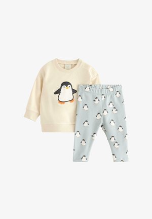 Completo pigiama con felpa crema che presenta un design di pinguino e pantaloni blu chiaro con stampe di pinguini ripetute. Realizzato in tessuto morbido.