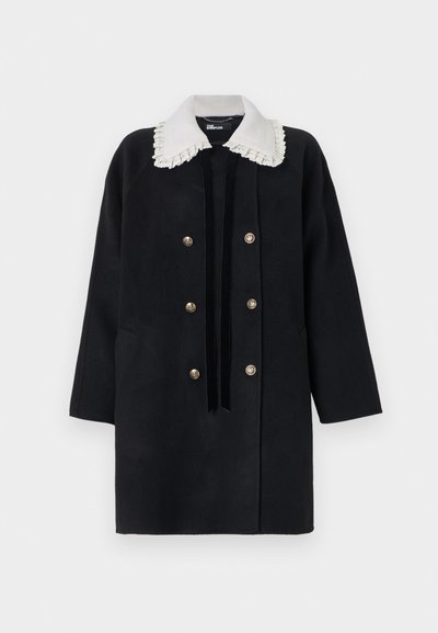 Μαύρο διπλόμπουτο παλτό με χρυσά κουμπιά, λευκό γιακά με δαντέλα και μαύρη βελούδινη κορδέλα δεμένη σε φιόγκο, απεικονίζεται σε απλό φόντο.