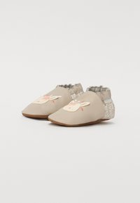 Myke beige sko med brodert kanindesign, elastisk mansjett for bedre passform, teksturert blomsterdesign på baksiden, og flat brun såle.