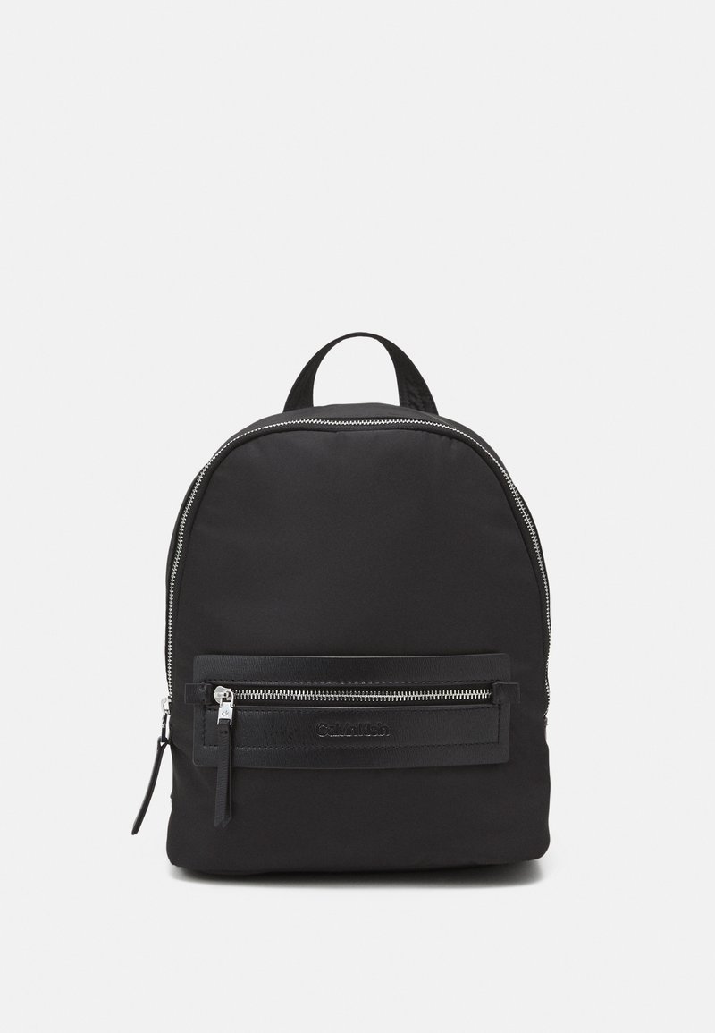 Black nylon backpack with a rounded shape, featuring a front zip pocket, silver hardware, a top handle, and a textured design.