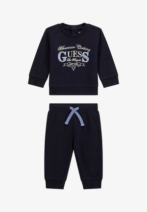 Felpa blu navy con logo stampato e scollo rotondo, abbinata a pantaloni jogger blu navy con vita elastica e lacci azzurri.