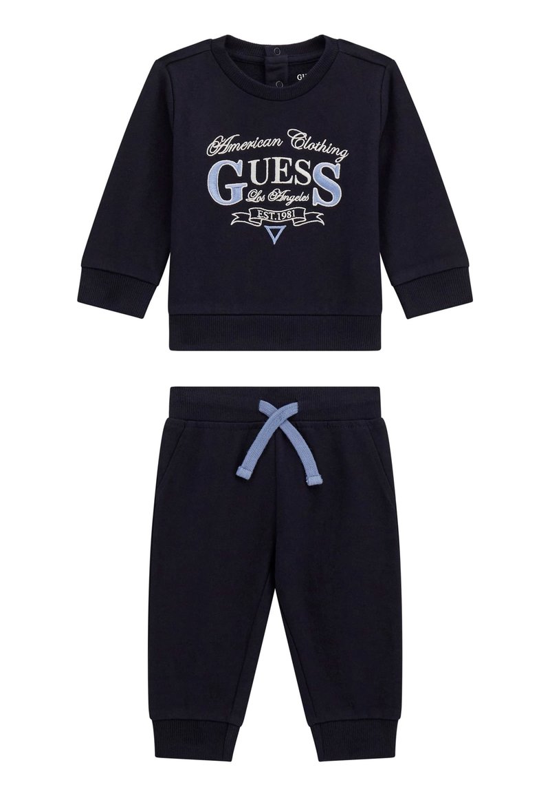 Marineblaue Sweatshirt mit aufgedrucktem Logo und Rundhalsausschnitt, kombiniert mit marineblauen Jogginghosen, die einen elastischen Bund und einen himmelblauen Kordelzug haben.