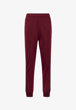 Pantalones deportivos de corte slim en color marrón granate con cintura y puños elásticos, que cuentan con franjas laterales negras y un pequeño logo negro en la parte superior del muslo.