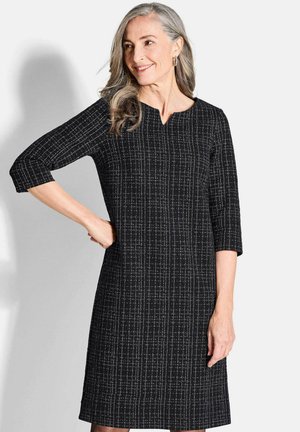 Robe noire à manches trois-quarts, décolleté en V, motif texturé de lignes blanches, longueur genou, tissu lisse.