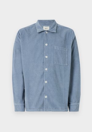 Camicia di corduroy blu con abbottonatura frontale, colletto, taschino singolo sul petto e maniche lunghe. Il tessuto presenta strisce verticali.