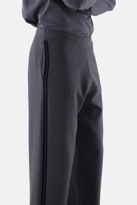 Grau maßgeschneiderte Hose mit glatter Textur, seitlichen Taschen und schwarzen vertikalen Streifen entlang der Nähte. Dezenter, strukturierter Bund.