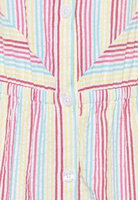 Šaty z pruhované tkaniny s vertikálními pruhy v červené, růžové, žluté a aqua. Bílé zapínání na knoflíky a nařasený pas.