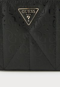 Čierna textúrovaná kabelka s trojuholníkovou zlatou nášivkou s názvom značky, so vzorovaným povrchom a designom s diamantom.