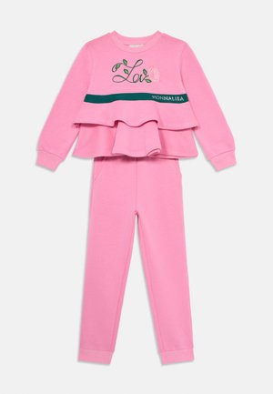 Rózsaszín pulóver szett réteges dizájnnal, zöld kiegészítőkkel és hímzett részletekkel. Puha anyag; tartalmaz egy egyező rózsaszín nadrágot.