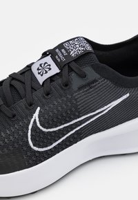 Sort atletiksko med tekstureret strikket overdel og hvid Swoosh-logo. Har en fremtrædende mærkat med QR-kode og snørebånd for sikker pasform.