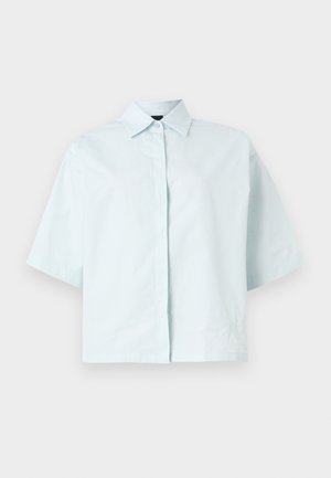 Chemise bleu clair à manches courtes avec col pointu, patte de boutonnage dissimulée et coupe ample et carrée.