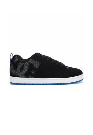 Zapatilla baja negra con logo oscuro gris con patrón, cordones negros, entresuela blanca y suela exterior azul visible desde el lateral.