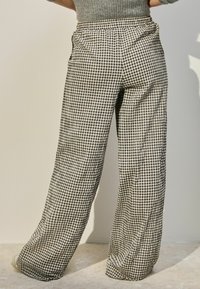 Zwart-witte geruite wijde broek met een ontspannen pasvorm, voorzien van een elastische tailleband en zijzakken, gemaakt van lichtgewicht stof.