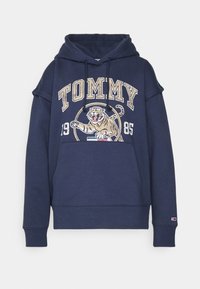 Sudadera azul marino de algodón, con un estampado gráfico de un tigre y la palabra "TOMMY" en dorado. Incluye un bolsillo frontal y capucha ajustable.