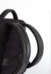 Musta reppu, jossa on pehmustetut nahkakahvat, teksturoitu kangasrunko ja säädettävät hihnat tyylikkäällä muotoilulla.