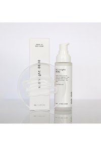 Crema per capelli leave-in in una elegante bottiglia bianca con erogatore, accanto a una piastra Petri trasparente contenente una sostanza cremosa bianca, tutto su una superficie riflettente.
