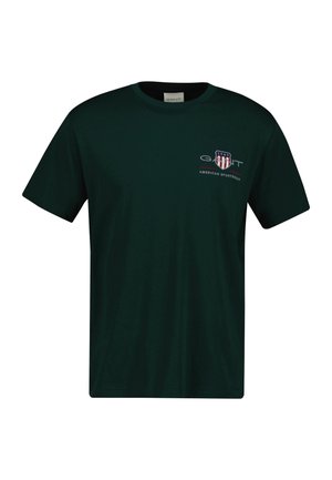 Sötétzöld, pamut póló, kerek nyakkivágással. Piros és fehér csíkos logóval és "GANT American Sportswear" felirattal rendelkezik.