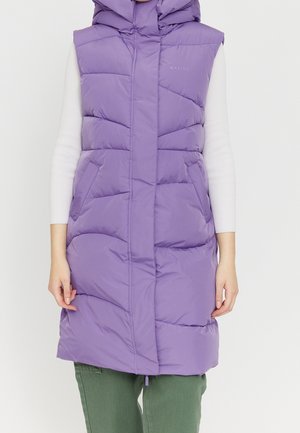 Doudoune sans manches violette avec capuche portée sur un haut blanc à manches longues et un pantalon vert, poches avant visibles.