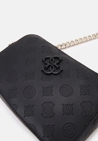 Musta nahkainen olkalaukku, jossa on kuviolaatta ja logo. Varustettu hopeisella ketjuhihnalla ja sileällä pinnalla. Suorakulmainen muoto.