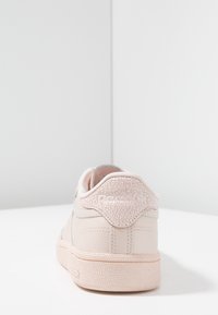 Jasnoróżowy skórzany sneaker z teksturowanym detalem na pięcie; wyposażony w miękkie wyściełanie wokół kostki oraz teksturowaną gumową podeszwę.