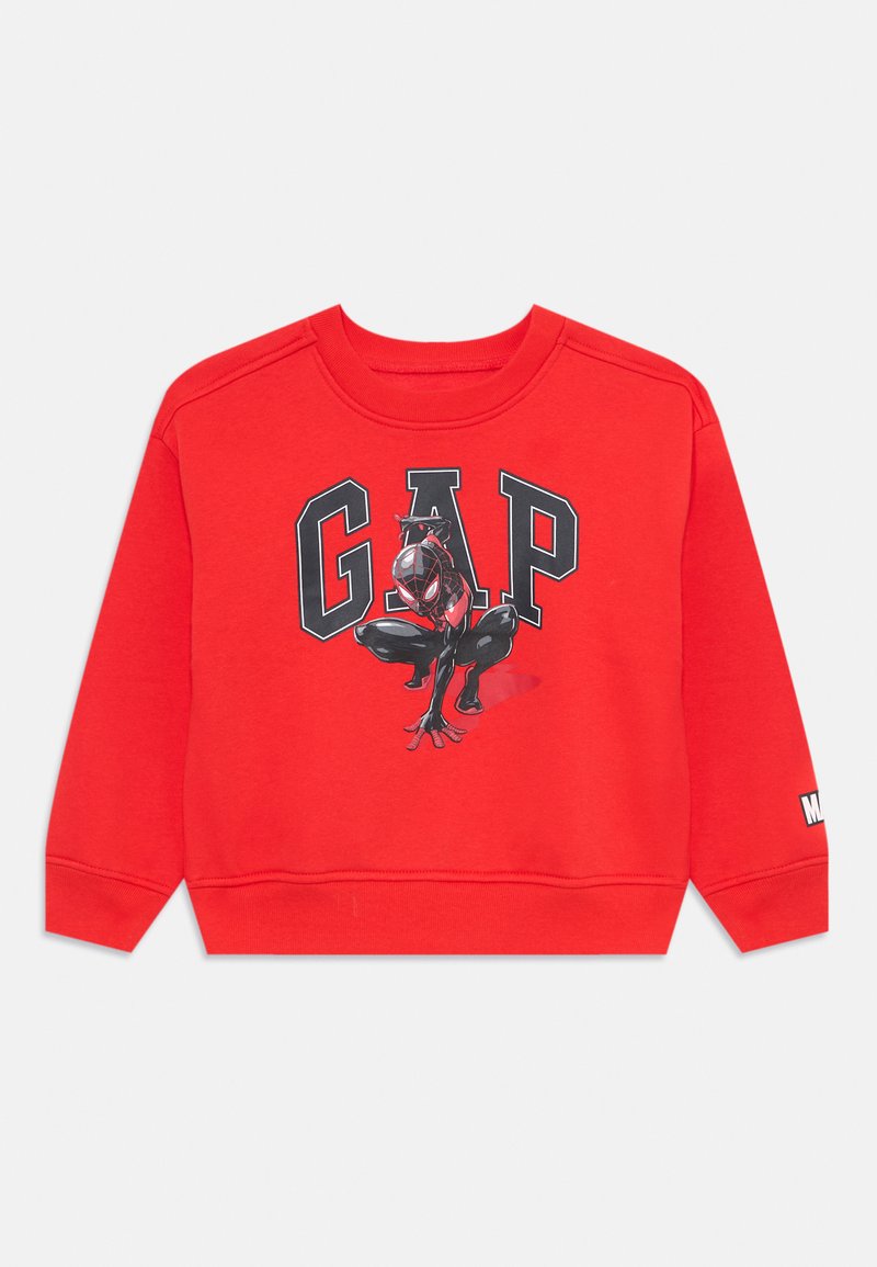Punane sviiter ribitud varrukate ja äärega, millel on suur "GAP" logo. Keskne graafika näitab musta ja punase karakterit.