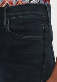 Dunkelblaue hoch taillierte Jeans aus Denim mit einer Vordertasche, dezentem Stich und glatter Textur ohne sichtbare Abnutzungen.