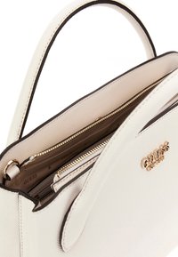 Borsa bianca con texture e bordi neri, manici superiori e logo in metallo dorato. L'interno presenta tasche con zip e foderato in tessuto.