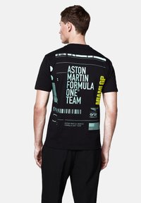 Czarna bawełniana koszulka z grafiką na plecach w miętowym zielonym i żółtym kolorze, przedstawiająca "Zespół Formuły 1 Aston Martin" oraz wzory.