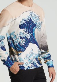 Camicia a maniche lunghe con un motivo a onda in blu, bianco e beige, realizzata in un tessuto morbido, con collo rotondo e polsini aderenti.