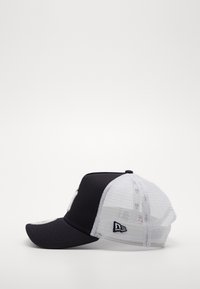 Schwarze Stoff-Baseballmütze mit einem weißen Netzrücken, gebogenem Schirm und gesticktem Logo auf der Vorderseite. Verstellbarer Snapback-Verschluss.