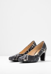 Černé a šedé lodičky s hadím vzorem, hladkým povrchem a kulatou špičkou, s robustním blokovým podpatkem.