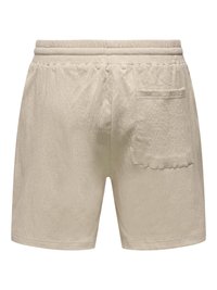 Short en éponge beige avec ceinture élastiquée et une poche plaquée à l'arrière côté droit.