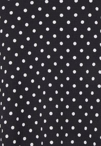 Tecido preto com uma superfície texturizada, apresentando um padrão repetido de pontos brancos em tamanhos variados, distribuídos uniformemente pelo material.