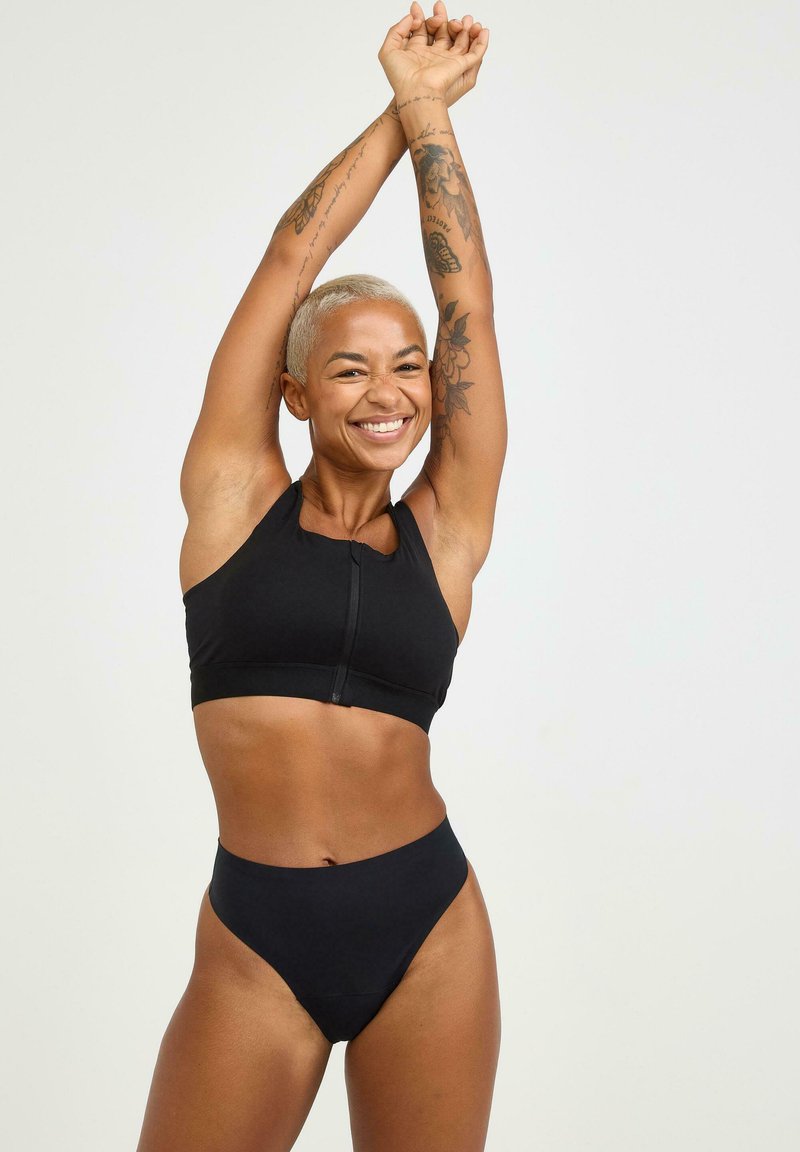 Schwarzes Sport-BH mit Reißverschluss vorne, Halter-Design und passendem hochgeschnittenem Bikini-Höschen. Glattes Material mit minimalen Nähten.