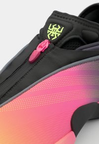 Scarpa sportiva nera e rosa con chiusura a zip, caratterizzata da un motivo a gradiente, dettagli tessurizzati e un logo giallo sulla parte superiore.