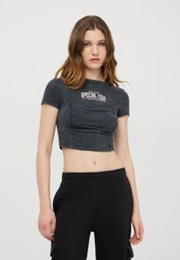 T-shirt crop nera con maniche corte, caratterizzata da una grafica bianca "SPECIAL TOUR" sul petto e una finitura testurizzata e sbiadita.