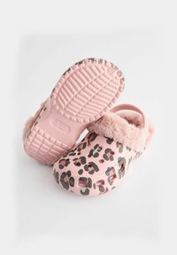 Sabots roses avec un motif léopard, dotés d'une doublure textile pelucheuse et d'une semelle en caoutchouc texturée pour une meilleure adhérence.