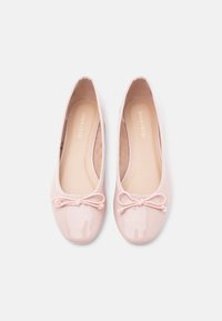Μπαλαρίνες σε ανοιχτό ροζ χρώμα, κατασκευασμένες από γυαλιστερό υλικό. Διαθέτουν στρογγυλεμένη μύτη, ελαστικές άκρες και διακοσμητικό φιόγκο στο μπροστινό μέρος.
