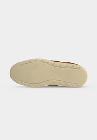 Semelle extérieure d'une chaussure marron avec une semelle en caoutchouc beige, lisse, présentant des motifs peu profonds le long des bords.